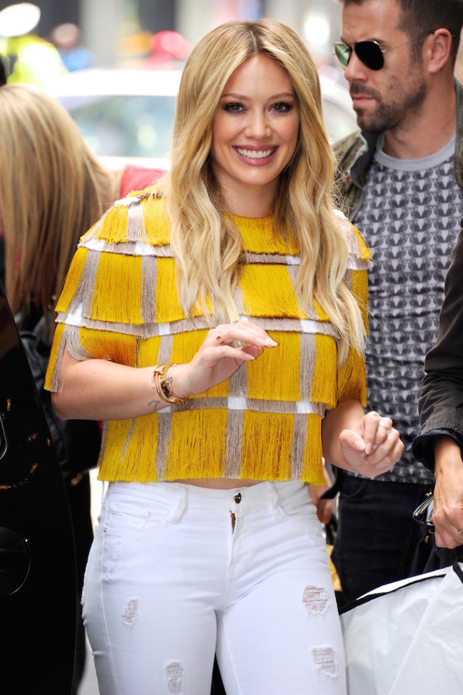 Hilary Duff seen out wearing a yellow and silver fringe top with white ripped jeans in NYC