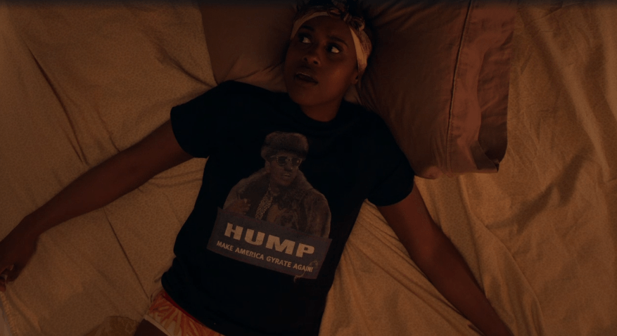 Issa lying in bed wearing HUMP Make America Gyrate Again 