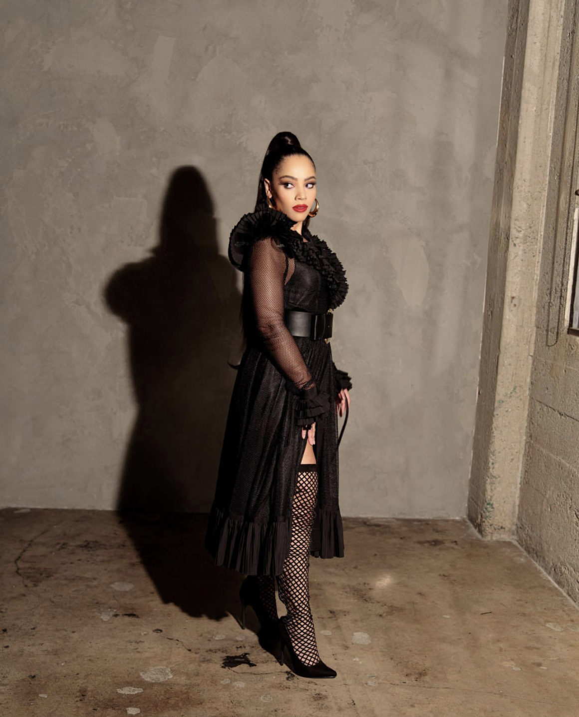 Bianca Lawson Posed for a Shoot Wearing UNTTLD Black Ruffled Fishnet Mesh Dress With Berna Peci Gold Hoops and Nasty Gal Accessories4