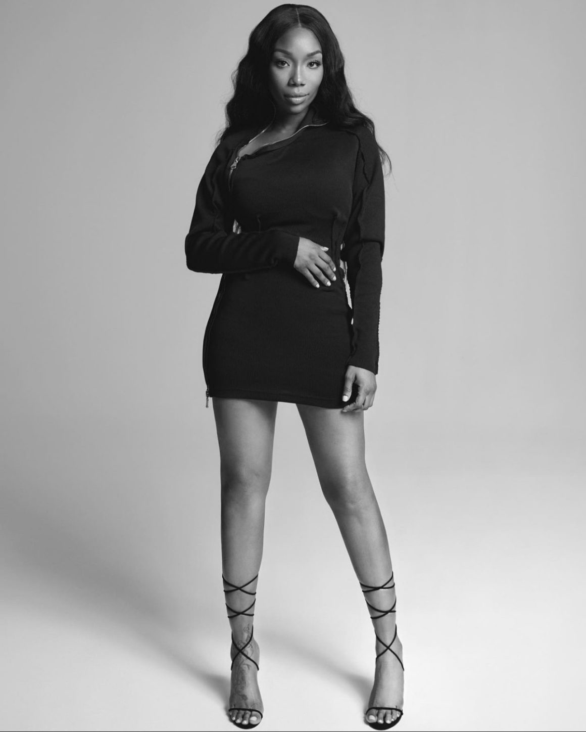 Brandy Stuns in Black and White Photoshoot Wearing Lionne Clothing Black Long Sleeve Zip Up Mini Dress and Femme LA Black Lace Up Sandals4