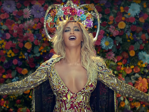 Beyonce Wears Abu Jani Sandeep Khosla Gold and Red Sequined Hand Embroidered Dress, a Laurel Dewitt Crown, and an Erickson Beamon Necklace in Coldplay’s Hymn for the Weekend Video