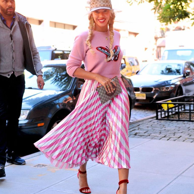 Get the Look: Beyoncé’s New York City Gucci GG Logo Cap, $1,200 Pink Intarsia Merino Wool Knit Butterfly Sweater, $2,200 Pleated Metallic Striped Stretch Silk Midi Skirt, $750 Lips Embellished GG Supreme Pouch, and $795 Saint Laurent Grace Velvet Sandals