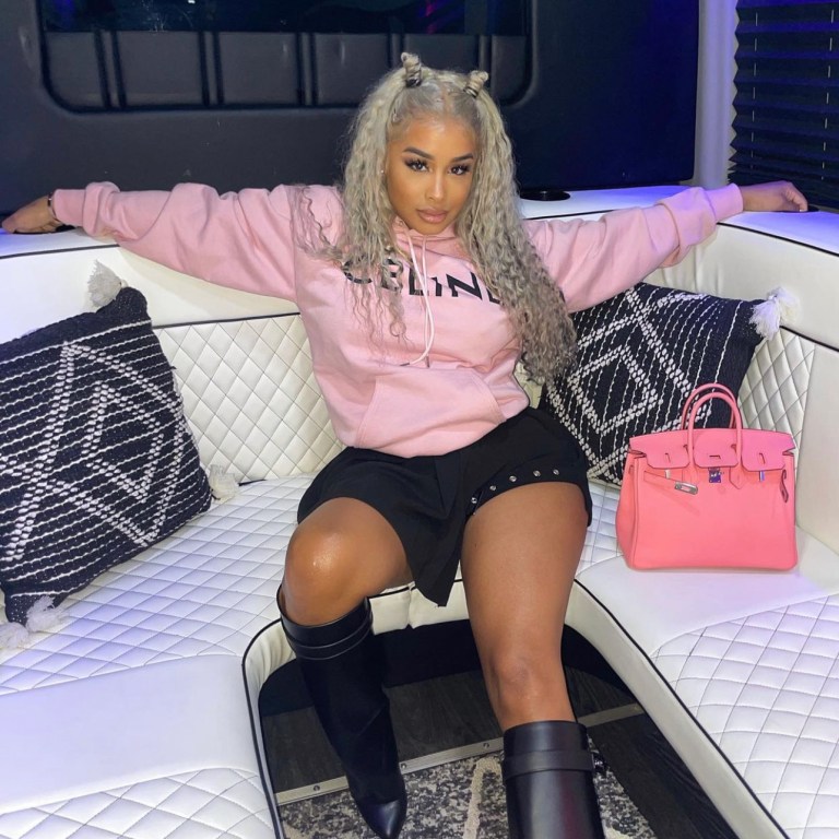 DreamDoll Keeps It Chic in a Black Buckle Pleated Skirt by Fashion Nova