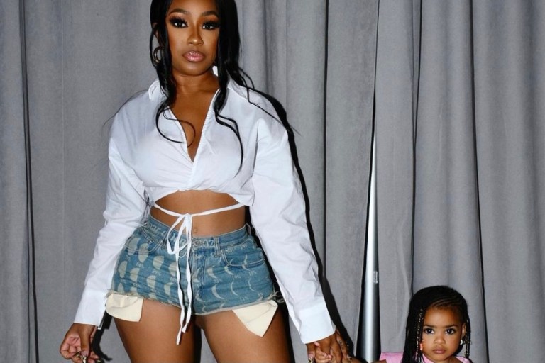 Wardrobe Inquiry: Yung Miami Attends Rookie USA’s New York Fashion Week Event With Her Family Wearing a White Tie Crop Top, Loewe Moon Print Shorts, and Bottega Veneta Accessories