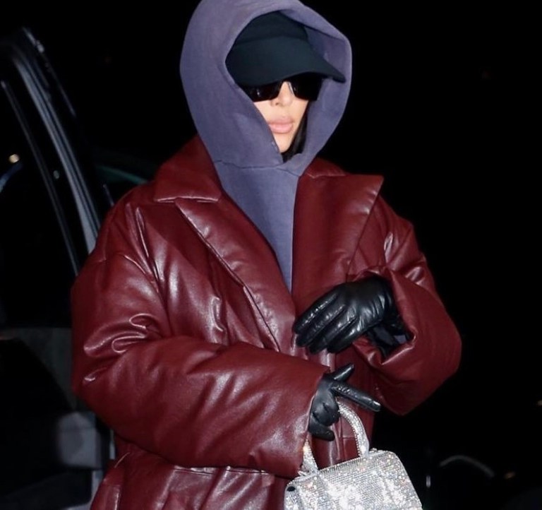 Kim Kardashian Bundles Up in Balenciaga Brown Padded Leather Coat, Purple Hoodie, and Crystal Handbag Paired With Vetements x Manolo Blahnik Pink Satin Thigh-High Boots While in NYC