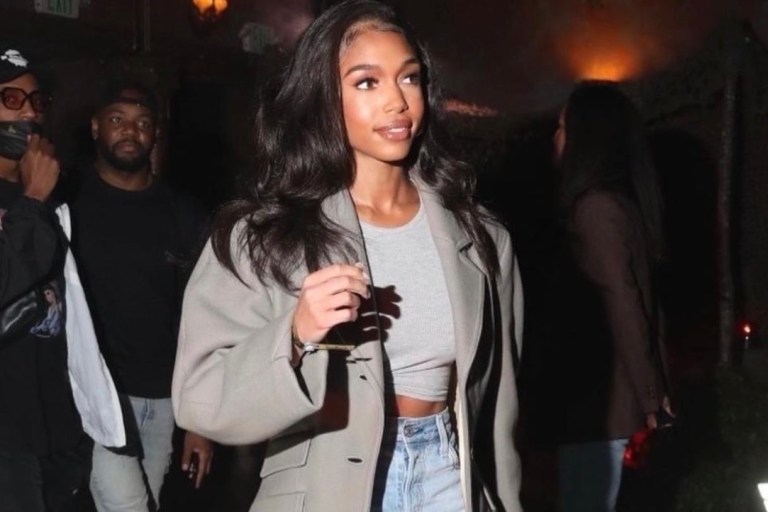 Lori Harvey Attends the Call of Duty: Vanguard Launch Party in LA Wearing Nanushka Long Grey Wool Coat, Naked Wardrobe Grey Knotted Top, Re/Done Jeans, and Clarité White Mesh Heels